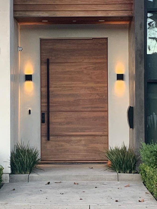 Modern wooden slatted main entrance door with vertical handle and wall lights