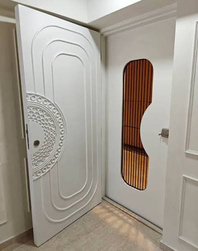 Elegant white carved safety door with intricate floral patterns and glass panel